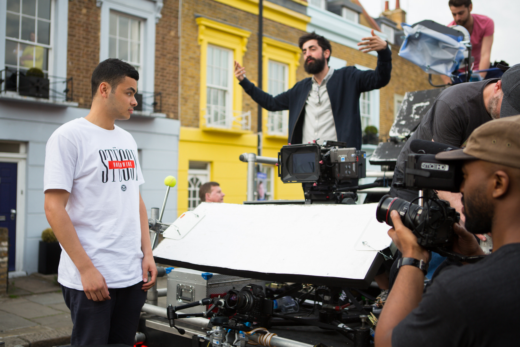 Michael Holyk directing on a London street, arms out, with the camera crew around him